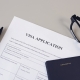 Visa application form, pen, eye glasses and passport on desk.