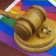 Wedding rings, wooden gavel and LGBT flags.