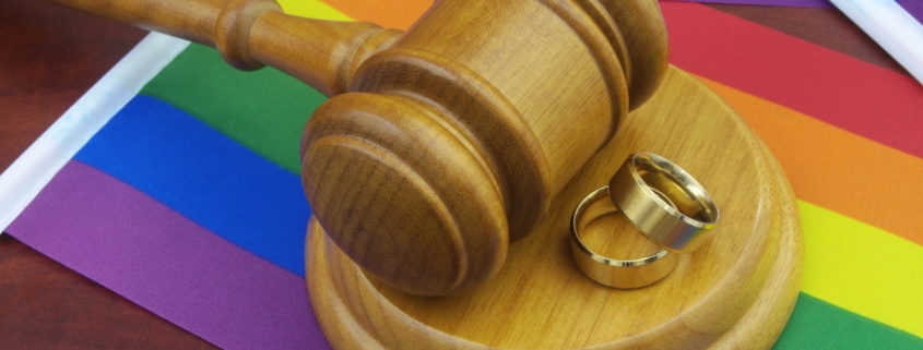 Wedding rings, wooden gavel and LGBT flags.