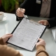 Closeup of insurance advisor handing application form to client during consultation