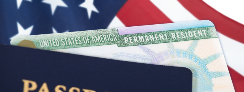 United States of America permanent resident card, green card, displayed with a US flag in the background and a passport in the foreground. Immigration concept.