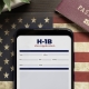 H-1b visa application concept: smartphone with USA H-1B visa application over a USA flag