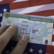 Permanent Resident Green card of United states of America on flag of USA. Above close up view.