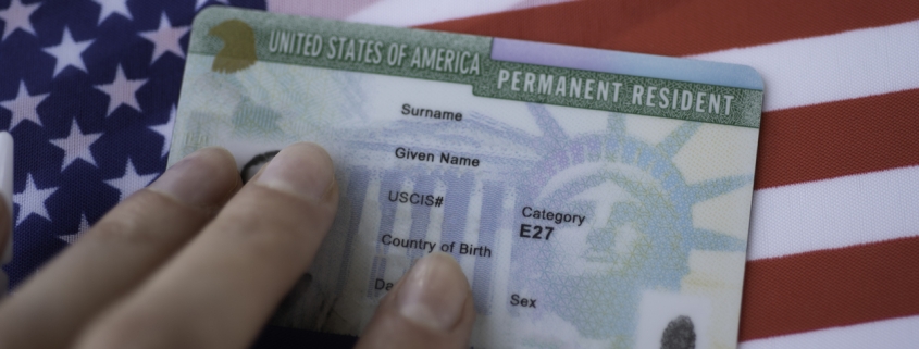 Permanent Resident Green card of United states of America on flag of USA. Above close up view.