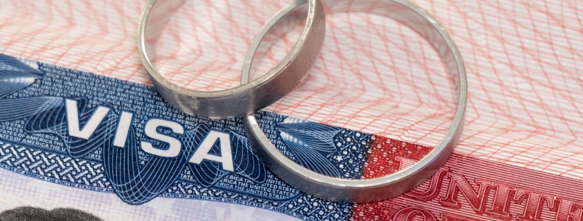 Newlyweds rings on a US visa close-up as an idea of marriage relocation.